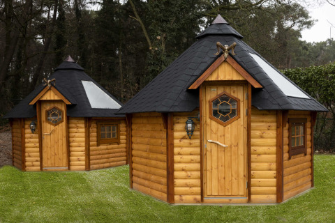 Twee achthoekige houten huisjes met zwarte daken op het gras bij Finse Kota, Costa Kabrita in Nederland.