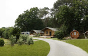 Panoramabillede af Safari tent lodge med geodætisk kuppel, træhytter og grønne omgivelser.