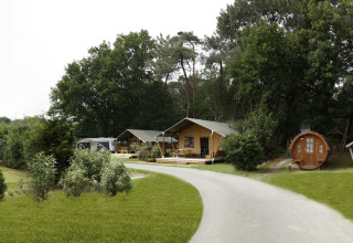 Panoramisch beeld van Safari tent lodge met koepeltent, houten huisjes en veel groen rondom.