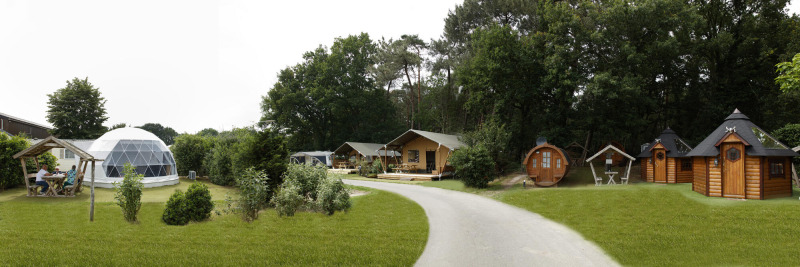 Panoramisch beeld van Safari tent lodge met koepeltent, houten huisjes en veel groen rondom.