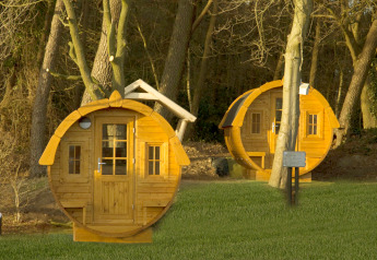 Twee ronde tiny houses genaamd Wijnvat bij Costa Kabrita in Nederland, gelegen tussen de bomen in de avondzon.