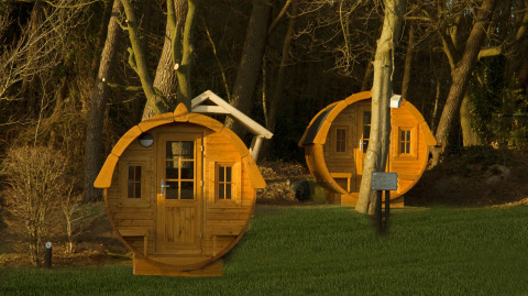 Twee ronde tiny houses, Wijnvat genaamd, tussen bomen bij Costa Kabrita in Nederland bij zonsondergang.