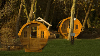 To runde tiny houses kaldet Wijnvat står blandt træerne ved Costa Kabrita i Holland ved solnedgang.