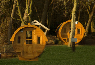 Twee ronde tiny houses, Wijnvat genaamd, tussen bomen bij Costa Kabrita in Nederland bij zonsondergang.