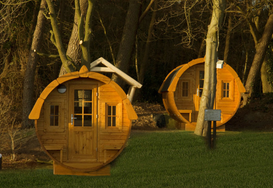 Twee ronde tiny houses, Wijnvat genaamd, tussen bomen bij Costa Kabrita in Nederland bij zonsondergang.