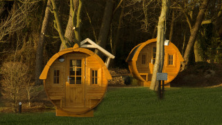 Twee ronde tiny houses genaamd Wijnvat bij Costa Kabrita in Nederland, gelegen tussen de bomen in de avondzon.