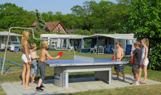 Niños y adultos juegan al tenis de mesa al aire libre en Costa Kabrita, parque vacacional en North-Brabant, Países Bajos.