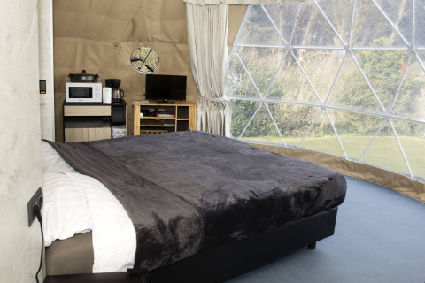 Vista interna del Dome a Costa Kabrita nei Paesi Bassi con letto, finestra panoramica e comfort moderni.