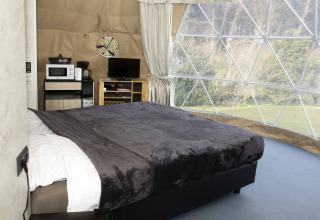 Vista interna del Dome a Costa Kabrita nei Paesi Bassi con letto, finestra panoramica e comfort moderni.