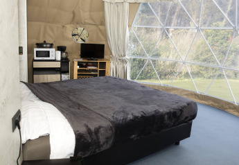 Innenaufnahme der Dome-Lodge bei Costa Kabrita in den Niederlanden mit Bett, Ausblick und Annehmlichkeiten.