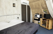 Modern Dome lodge at Costa Kabrita in the Netherlands with bed, wardrobe, small kitchen area and TV.