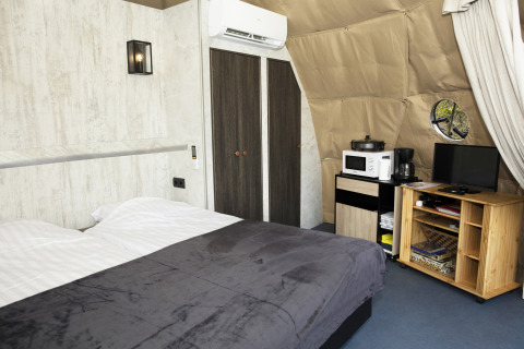 Komfortable Dome-Lodge bei Costa Kabrita in den Niederlanden mit Bett, Schrank, TV und Küchenzeile.