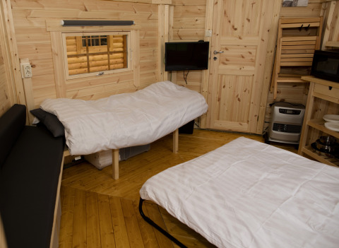Acogedor interior de la tiny house Finse Kota en Costa Kabrita, Países Bajos, con dos camas y paredes de madera.