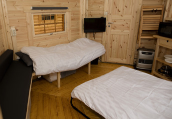 Acogedor interior de la tiny house Finse Kota en Costa Kabrita, Países Bajos, con dos camas y paredes de madera.