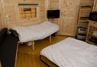 Accogliente interno della tiny house Finse Kota a Costa Kabrita nei Paesi Bassi con due letti e pareti in legno.
