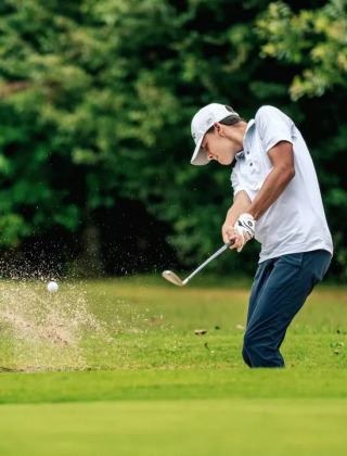 Golfer schlägt Ball aus dem Sandbunker im Camping Castel L'Orangerie de Lanniron, Bretagne, Frankreich.