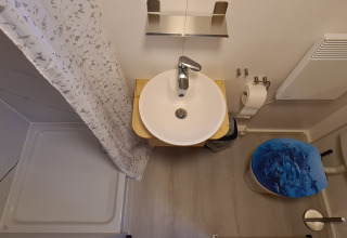 Compact bathroom in a tiny house at Vakantiepark 't Urkerbos, featuring sink, shower, and toilet.
