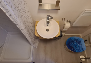 Lille badeværelse i et tiny house på Vakantiepark 't Urkerbos med bruser, håndvask og toilet.