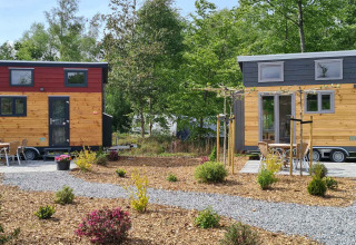 Dos casas diminutas en Tiny House en Vakantiepark 't Urkerbos, Países Bajos, rodeadas de jardines verdes.