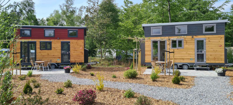 Deux tiny houses au Tiny House du Vakantiepark 't Urkerbos aux Pays-Bas, entourées de plantes et sentiers.