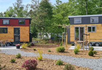 Twee tiny houses bij Tiny House op Vakantiepark 't Urkerbos in Nederland, omgeven door tuin en paden.