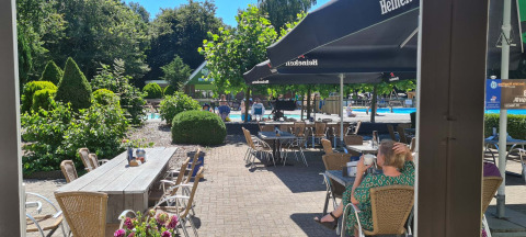 Zona caffè all'aperto soleggiata con vista piscina al Vakantiepark 't Urkerbos, Flevoland, Paesi Bassi.
