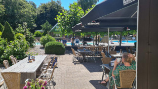 Cafetería al aire libre soleada con vistas a la piscina en Vakantiepark 't Urkerbos, Flevoland, Países Bajos.