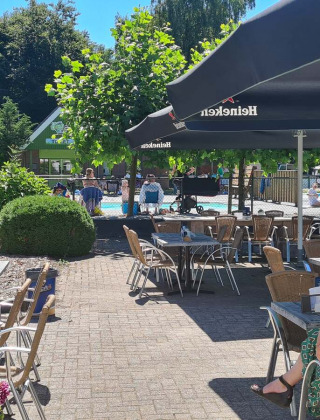 Cafetería al aire libre soleada con vistas a la piscina en Vakantiepark 't Urkerbos, Flevoland, Países Bajos.