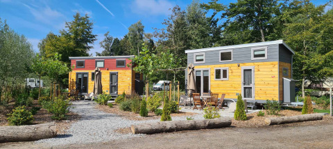 Tiny Houses au Vakantiepark 't Urkerbos aux Pays-Bas, entourées de verdure et de coins détente extérieurs.