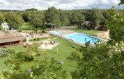 Udsigt over feriepark med swimmingpool, legeplads og grønne områder i Vakantiepark 't Urkerbos, Flevoland.