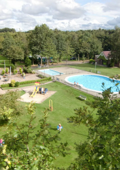 Vista del parque vacacional con piscina, zonas verdes y área de juegos en Vakantiepark 't Urkerbos, Flevoland.