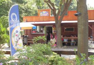 Ice cream shop at Vakantiepark 't Urkerbos, Flevoland, Netherlands, with customers and leafy surroundings.