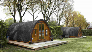 Glamping Pod lodges at Costa Kabrita in the Netherlands, featuring cozy wooden cabins in a green setting.