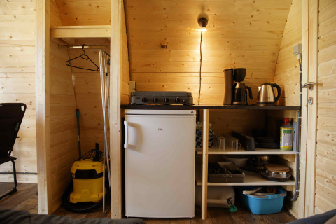 Kitchen area inside a Glamping Pod at Costa Kabrita in the Netherlands, featuring fridge and appliances.