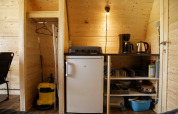 Kitchen area inside a Glamping Pod at Costa Kabrita in the Netherlands, featuring fridge and appliances.