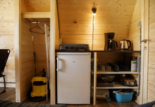 Kitchen area inside a Glamping Pod at Costa Kabrita in the Netherlands, featuring fridge and appliances.