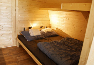 Cozy wooden Glamping Pod bedroom with double bed, Costa Kabrita lodge in the Netherlands, neatly made up.
