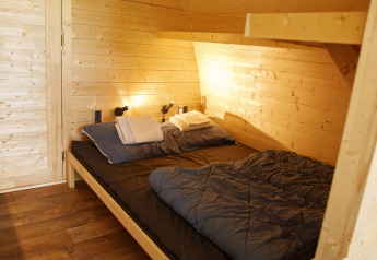 Cozy wooden Glamping Pod bedroom with double bed, Costa Kabrita lodge in the Netherlands, neatly made up.