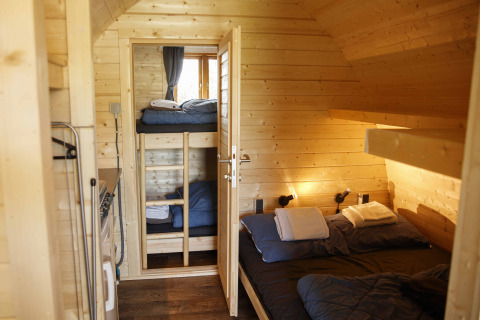 Acogedora cabina glamping de madera con cama doble y literas en Costa Kabrita, Países Bajos.