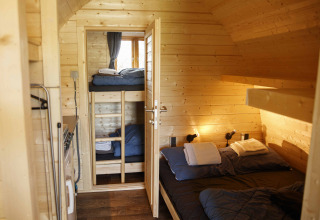 Knusse houten glamping pod met dubbel bed en stapelbedden bij Costa Kabrita in Nederland.