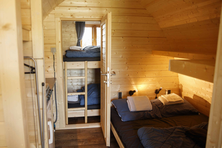 Gemütliches Glamping Pod aus Holz mit Doppelbett und Etagenbetten bei Costa Kabrita in den Niederlanden.