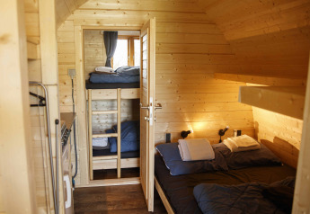 Acogedora cabina glamping de madera con cama doble y literas en Costa Kabrita, Países Bajos.