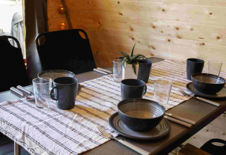 Sfeervol gedekte tafel voor vier personen in een houten Glamping Pod bij Costa Kabrita, Nederland.