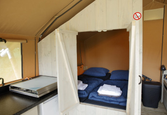 Indvendigt billede af Safari-teltet ved Costa Kabrita i Holland med senge, dyner og køkkenudstyr.