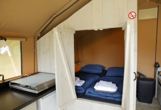 Interno di una tenda Safari presso Costa Kabrita nei Paesi Bassi con letti, lenzuola e piccola cucina.