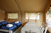 Interieur van een safaritentlodge met twee bedden en eettafel bij Costa Kabrita in Nederland.
