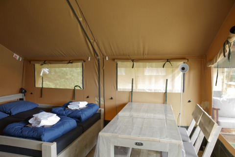 Indvendig udsigt over en safari-teltlodge med to senge og et spisebord på Costa Kabrita, Holland.