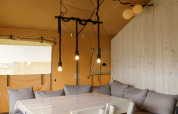 Interieur van de Safaritent bij Costa Kabrita in Nederland met eettafel, stoelen en zithoek.