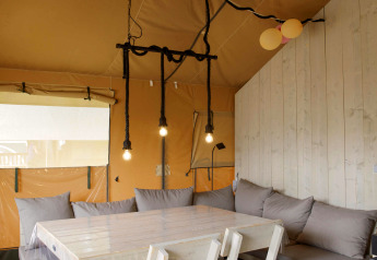 Binnenzicht van de safaritent bij Costa Kabrita in Nederland met tafel, stoelen en zithoek.