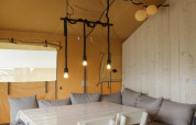 Indvendigt billede af Safari-teltet ved Costa Kabrita i Holland med bord, stole og sofaområde.